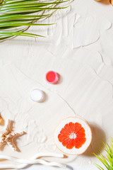 Wonderful beach. Lipstick, lip gloss, lip balm lie on the sand, surrounded by juicy fruits,...