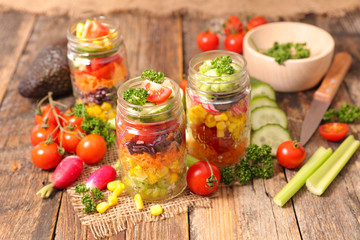 colorful vegetable salad in jar with radish, cucumber, tomato and celery