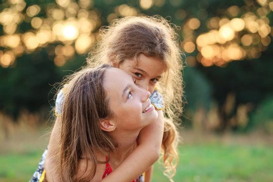 Two Cute little girls hugging and smiling at the countryside. Happy kids spending time  outdoors