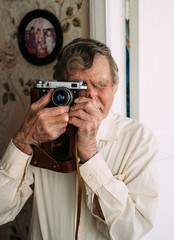 Portrait of a beautiful old man with old camera. Vintage, retro style. Senior Man Camera Photography.