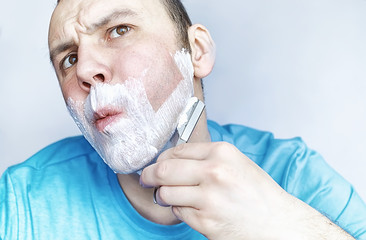 A man shaves in front a mirror. Shaving foam. Disposable razor.