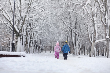 Snow-covered winter park and benches. Park and pier for feeding ducks and pigeons.Family on a walk in the snow covered the park.