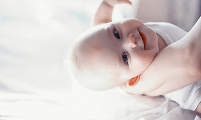 Fototapeta premium Maternity concept. A young mother feeds her little baby. First lure and breastfeeding. Family in white clothes.