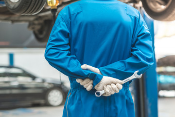 Car Mechanic Ready For Work. Auto Mechanic with Large Wrench in Hands. Ideas How to Fix the Problem.Male mechanics at the garage fixing a car