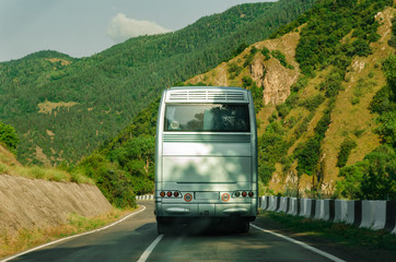 Rear side of bus. Back view. Blank white bus on mountain highway.