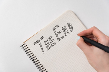 Notice in the notebook The End. Handwritten text. Hand with pen and notepad on white background....