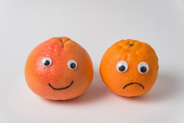 Funny food - tangerines couple with eyes. Funny and sad tangerines on a white background.