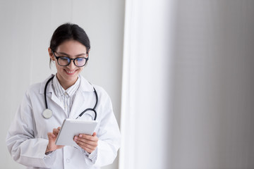 A doctor woman has to work with touching the tablet at the hospital with smiling and happiness.