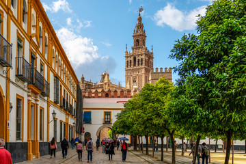 Obraz premium Sewilla, Andaluzja, Hiszpania - 9 kwietnia 2019: Wiosenne piękno Sewilli w centrum miasta - ciepła pogoda i ludzie, majestatyczna architektura. Gotycka katedra w Sewilli. Dzwonnica La Giralda z pomnikiem El Giraldillo.