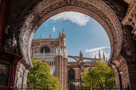 Beauty of Seville Cathedral. View to cathedral North facade and Oranges yard through the arch gate. Largest Gothic church in the world. Cathedral of Saint Mary of the See, Andalusia, Spain, Europe
