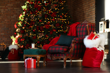 Obraz premium Santa Claus bag near armchair in room with Christmas tree