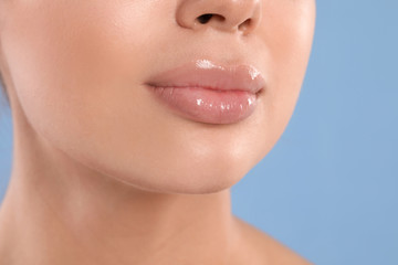 Young woman with beautiful full lips on light blue background, closeup