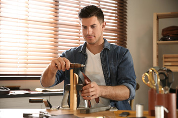 Man burnishing edges of leather belt in workshop