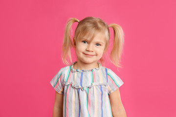 Portrait of cute little girl on pink background