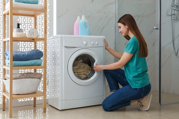 Woman near washing machine in bathroom. Laundry day