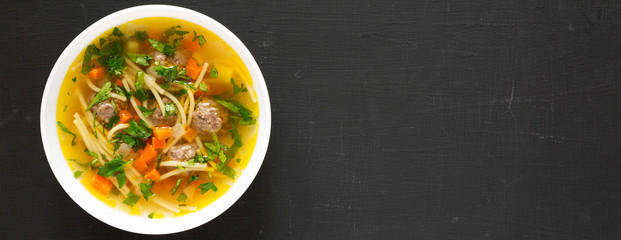 Homemade Sopa a La Minuta in a white bowl on a black surface, top view. Flat lay, overhead, from above. Space for text.