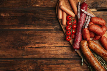 Different tasty sausages on wooden table, top view. Space for text