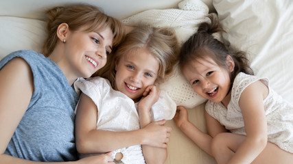Top view of mom relax in bed with little daughters