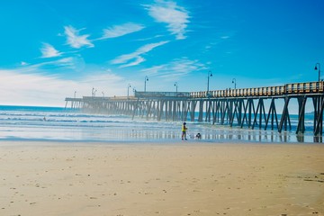 Surfers on the wooden pier of Pismo Beach in California