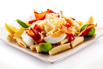 Penne pasta with cheese, bacon, boiled eggs and vegetables on white background
