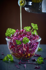 red cabbage salad and pouring olive oil in a glass bowl