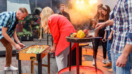 Handsome man is grilling delicious food on grill for his friends at barbecue party outdoors. Picnic time, weekend. Slow motion