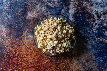 Caramel Popcorn in Glass Bowl on Grey Surface.