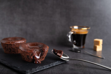 Warm chocolate lava cake on a black plate with a cup of coffee on a dark background
