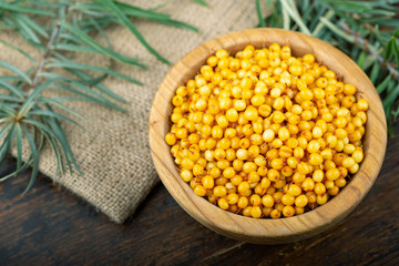 Ripe sea-buckthorn berries in a wooden bowl on the table.
