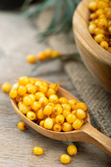 Ripe sea-buckthorn berries in a wooden spoon on the table.