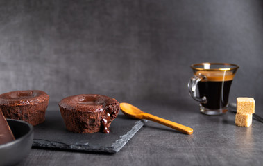 Warm chocolate lava cake on a black plate with a cup of coffee on a dark background