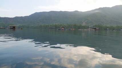 Wide shot of a lagoon with the clouds reflected in the waters at a fishing village.