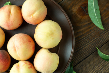 Ripe peaches in  plate on wooden background.