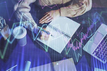 Forex graph on hand taking notes background. Concept of research. Double exposure