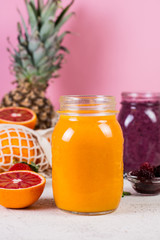 Fototapeta na wymiar a jar of yellow tropical smoothie on a pink background.