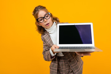 funny smart caucasian schoolgirl with glasses in a business suit and a jacket with a laptop with a...