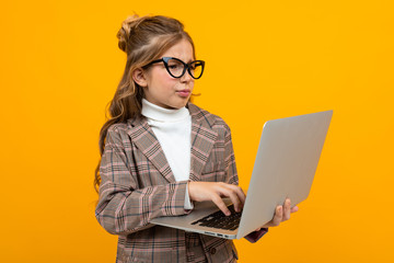 caucasian girl with glasses in a business suit with a laptop in hands on a yellow background