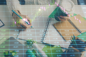 Financial forex graph displayed on hands taking notes background. Concept of research. Multi exposure