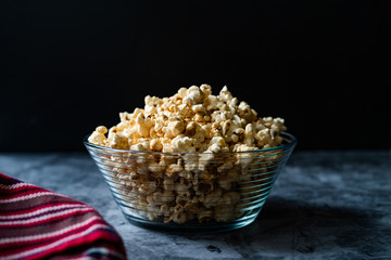 Caramel Popcorn in Glass Bowl on Grey Surface.