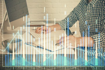 Double exposure of stock market chart with man working on computer on background. Concept of...