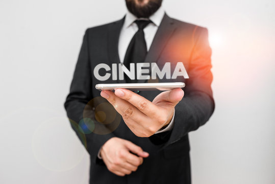 Handwriting text writing Cinema. Conceptual photo theater where movies are shown for public entertainment Movie theater Male human wear formal work suit hold smart hi tech smartphone use one hand