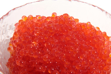 Red caviar lies in a glass bowl. Isolated object on a white background