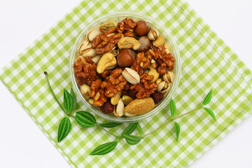Selection of walnuts, hazelnuts, cashew nuts and almonds in plastic box on checkered green and white cloth