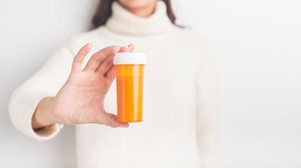Unrecognizable woman advertising herb capsules in bottle