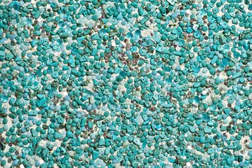 Texture of various jewels on a white background. Blue and cyan stones. Beads and necklaces are glued to the wall.