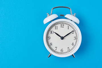 Vintage white alarm clock on the blue backround with copy space. Time concept