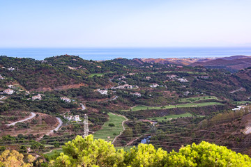 A mountain landscape on evening time. View of the valley and of the sea from the snake route A-397 Ronda - Malaga. Spain, Andalusia.