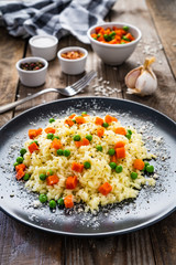 Risotto with carrot and grean peas on wooden background