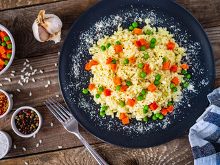 Risotto with carrot and grean peas on wooden background