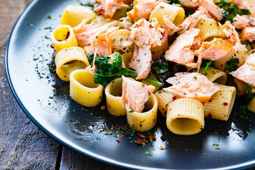 Pasta with salmon and spinach on wooden background